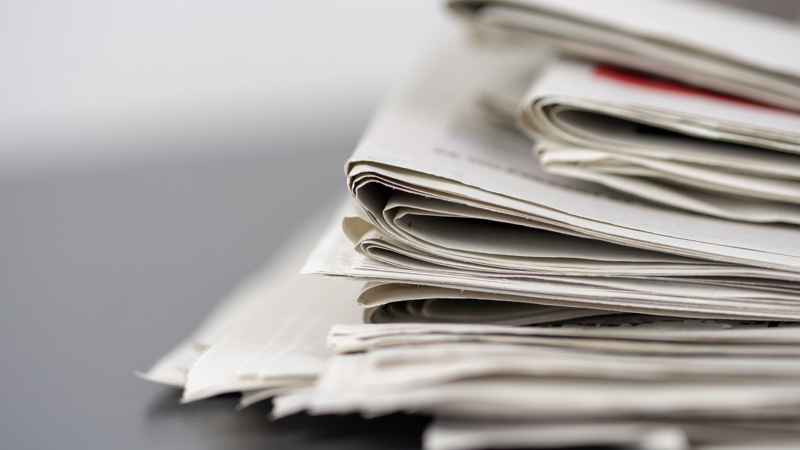 Folded printed newspapers stacked on a table.