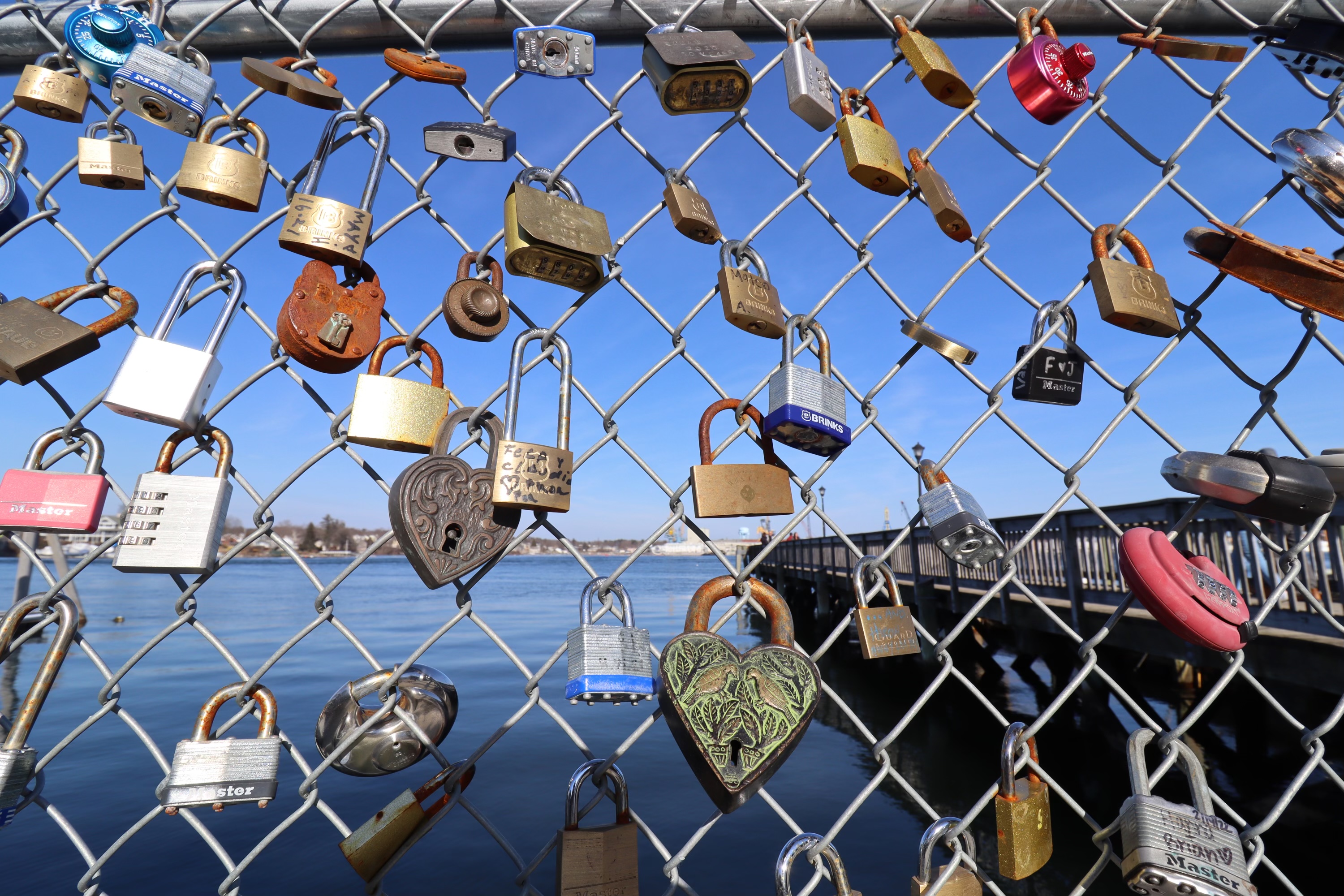 Assorted padlocks attached to a chain link fence, used as a visual metaphor for pinned workflow dependencies.