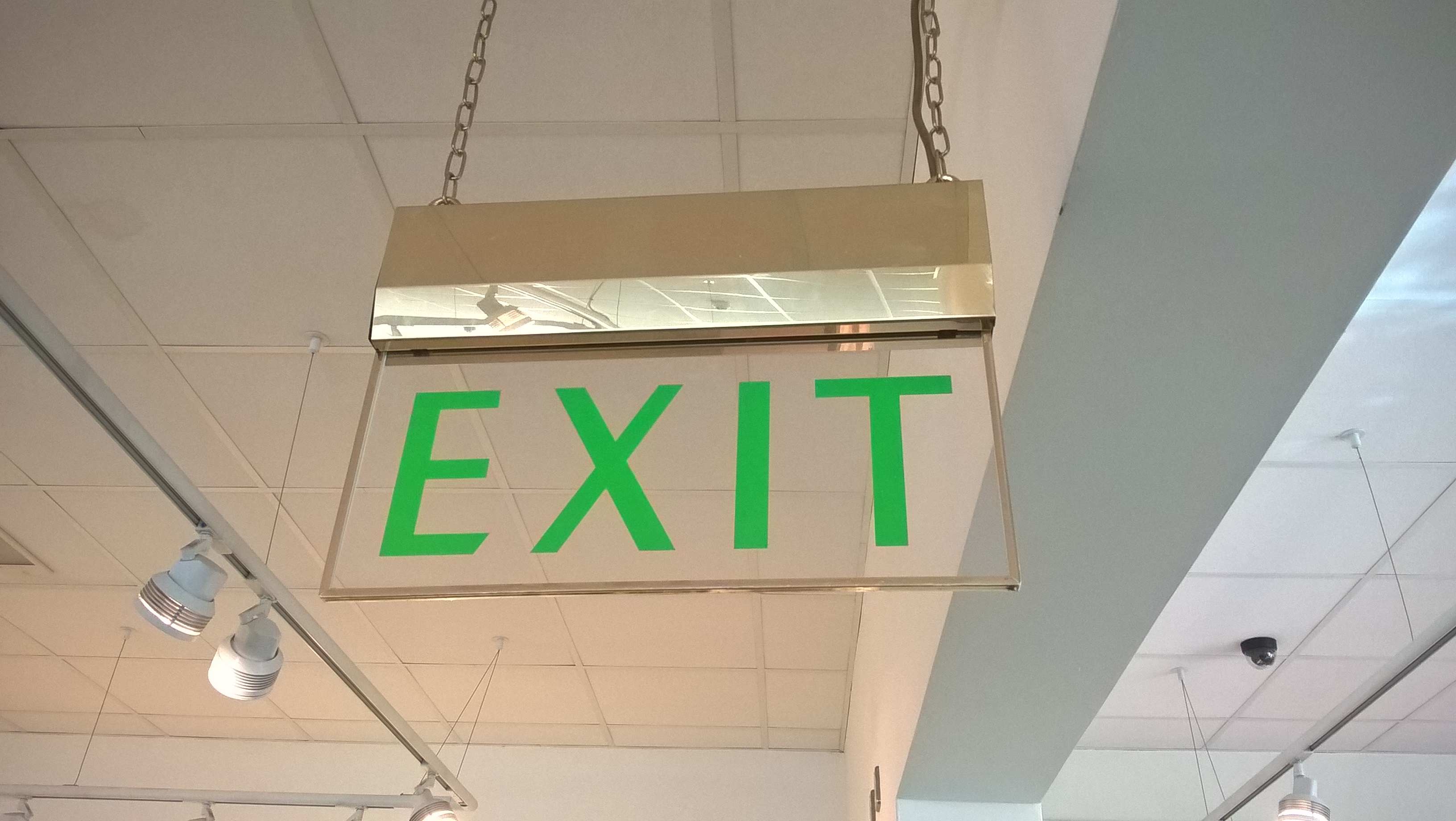 Green exit sign hanging from a ceiling.